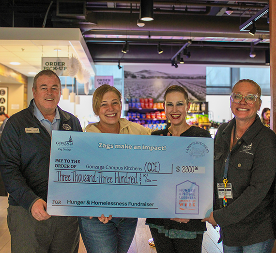 A woman in graduation cap and gown holds up her degree and smiles